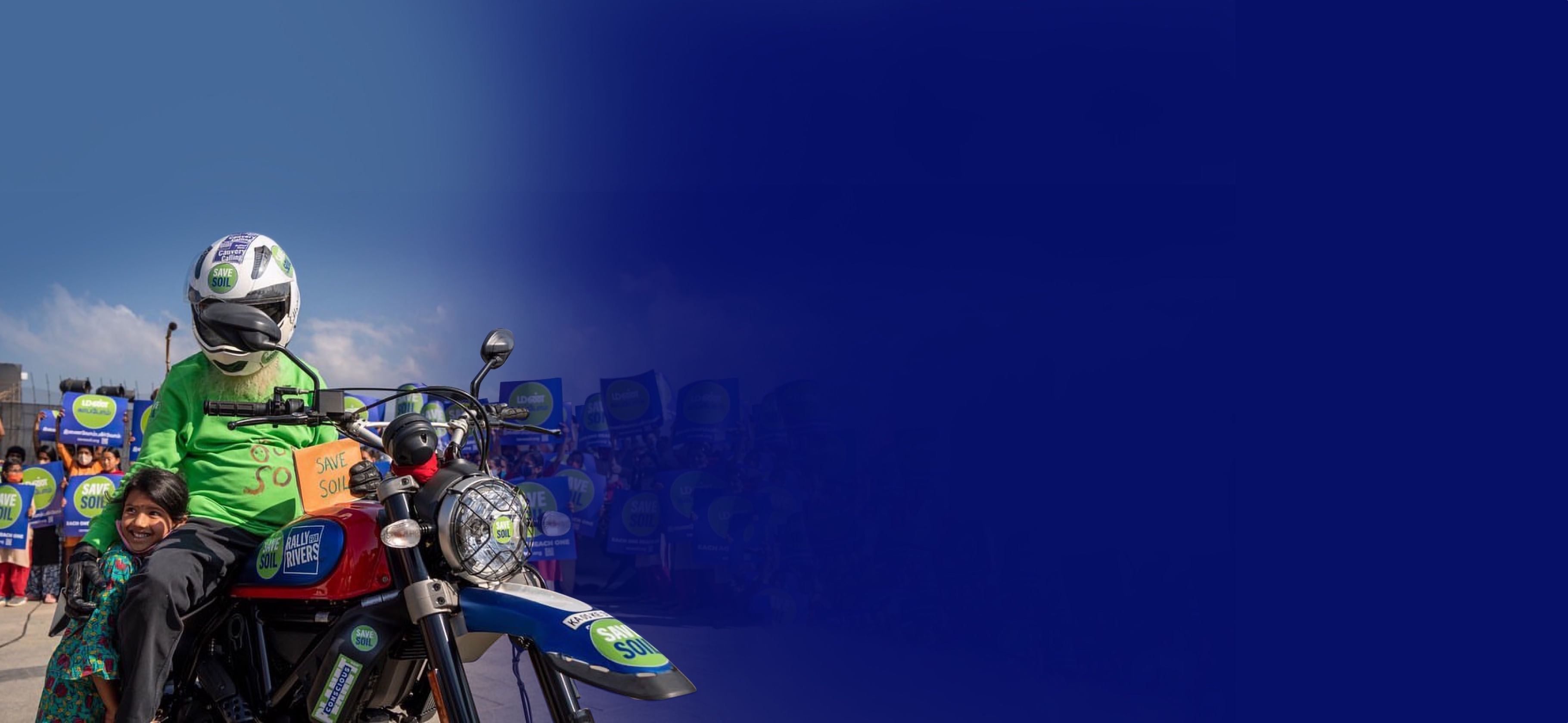 Садхгуру на мотоцикле с логотипом «Спасём Почву», рядом с ребёнком